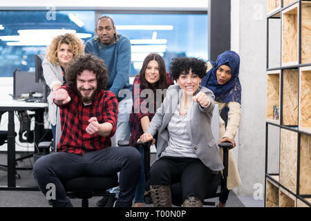 multiethnics startup business team of software developers having fun while racing on office chairs,excited diverse employees laughing enjoying funny a Stock Photo