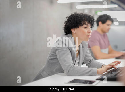 young female software developer using desktop computer while writing programming code at modern creative startup office Stock Photo
