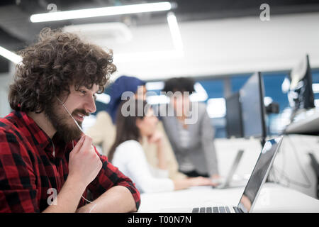 young multiethnics business team of software developers working together using laptop and desktop computer while writing programming code at modern st Stock Photo