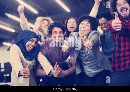 portrait of young excited multiethnics business team of software developers standing and looking at camera while celebrating success at modern startup Stock Photo