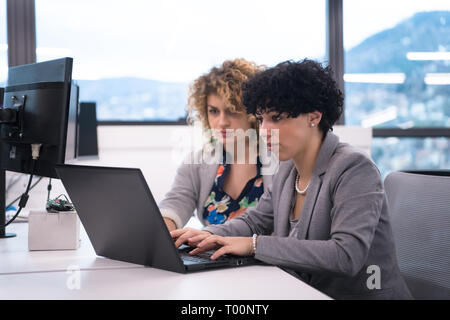 group of young female software developers using laptop computer while writing programming code at modern creative startup office Stock Photo