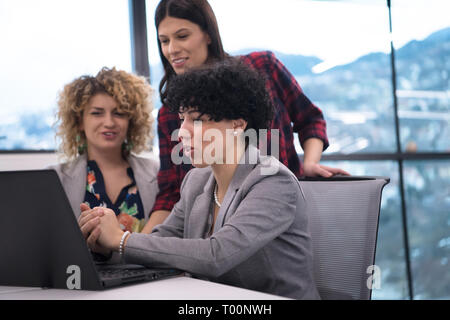 group of young female software developers using laptop computer while writing programming code at modern creative startup office Stock Photo