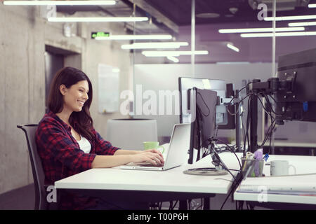 young female software developer using laptop computer while writing programming code at modern creative startup office Stock Photo