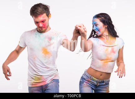 Holiday, social dance, holi and people concept - Happy couple having fun and dancing bachata or kizomba covered in paint on white background Stock Photo
