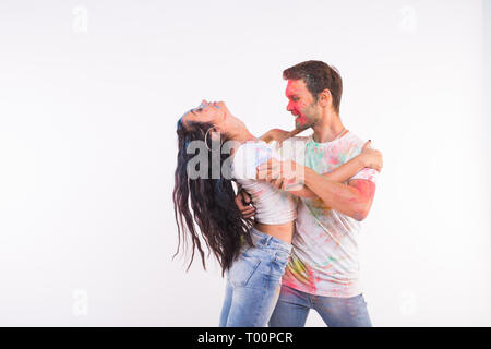 Holiday, social dance, holi and people concept - Happy couple having fun covered in paint and dancing bachata or kizomba on white background with copy Stock Photo