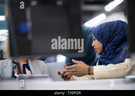 black muslim female software developer working together with her multiethnics business team using computer while writing programming code at modern st Stock Photo