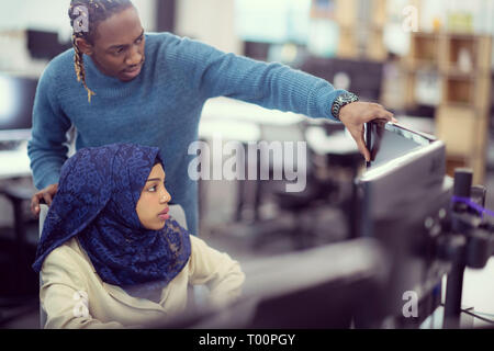 black muslim female software developer working together with her african american male colleague using computer while writing programming code at mode Stock Photo