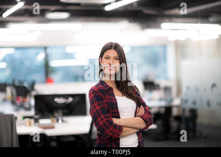 Portrait of young successful female software developer with with crossed arms at modern startup office Stock Photo