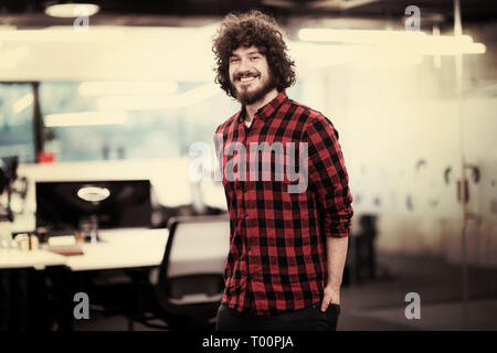 Portrait of young smiling successful male software developer standing at modern startup office Stock Photo