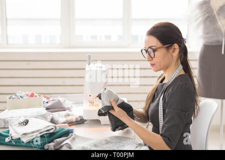 People, tailor and fashion concept - High angle view portrait of smiling fashion designer in glasses sitting at a table Stock Photo