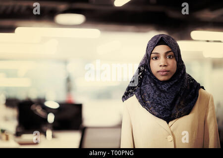 Portrait of young muslim african american female software developer with blue scarf standing at modern startup office Stock Photo