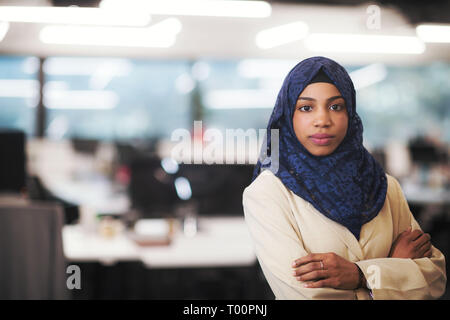 Portrait of young muslim african american female software developer with blue scarf standing at modern startup office Stock Photo
