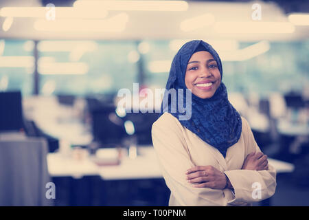 Portrait of young muslim african american female software developer with blue scarf standing at modern startup office Stock Photo