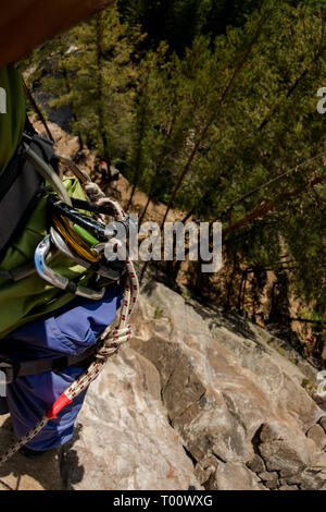 Climber's legs hanging on a rope in a harness, first person view from top to bottom Stock Photo