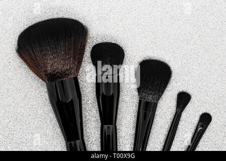 Black and brown makeup brushes on shiny silver background surface Stock Photo