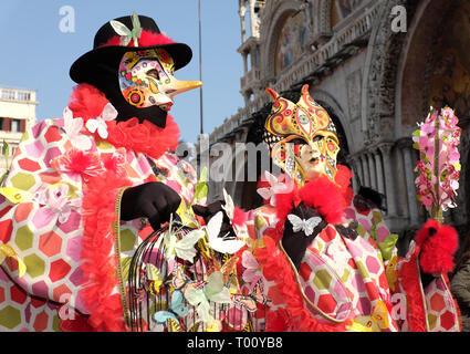 Couple dressed in traditional mask and costume for Venice Carnival standing in Piazza San Marco, Venice, Veneto, Italy Stock Photo