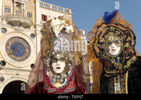 Couple dressed in traditional mask and costume for Venice Carnival standing in Piazza San Marco, Venice, Veneto, Italy Stock Photo