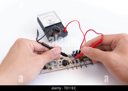 Technician hand with multimeter probes repairing circuit board Stock Photo