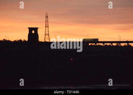 Silhouette of one of the Britannia bridge towers with a lorry travelling over it and a electricity pylon. Stock Photo