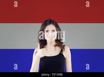 Love Netherlands! Happy woman smiling and showing thumb up on netherlandish flag background Stock Photo