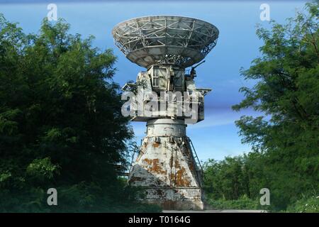 The ruins of an abandoned radar site in As Matuis, Saipan, Northern Mariana Islands framed by green trees Stock Photo