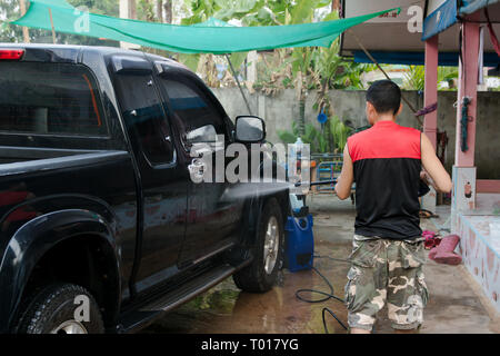 Man washing black pickup truck car with high pressure washer Stock Photo