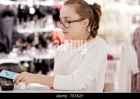 woman paying bill through smartphone using NFC technology in restaurant, cafe, bar. Stock Photo