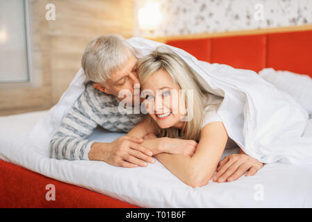 Mature love couple looks at each other in bedroom Stock Photo