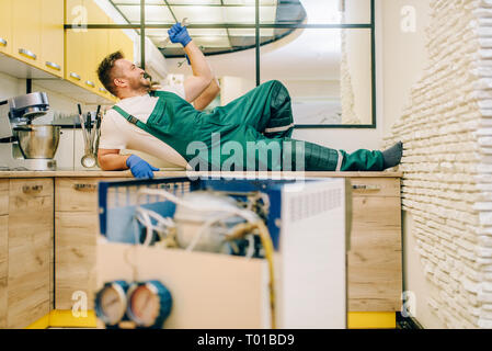 Worker in uniform lies against refrigerator Stock Photo