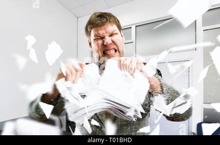 Angry businessman tearing stacks of paper Stock Photo