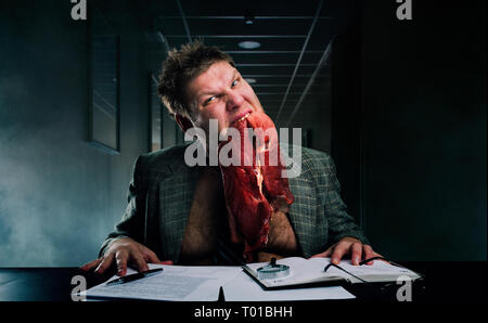 Crazy businessman with piece of raw meat in mouth Stock Photo