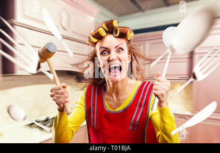 Crazy housewife in apron cooking, cookware flying Stock Photo