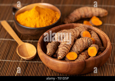 Turmeric roots and powder in close up. Selective focus on turmeric roots Stock Photo