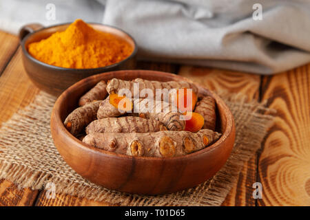 fresh turmeric roots and powder on wooden background. Selective focus on turmeric roots Stock Photo