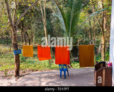 Buddhist orange monk robes drying on bamboo pole washing line, Wat Phoy Khuay monastery, Luang Prabang, Laos Stock Photo