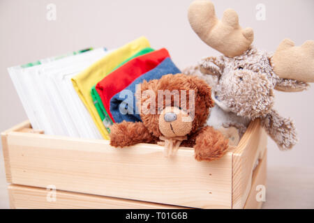 Donation concept. Donate box with kids clothes, books, school supplies and toys. TTeddy bear and moose toy Stock Photo