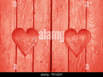 Close up two heart shaped elements, symbol of love, romance and togetherness, wood carved cut in wooden planks texture background, coral pink painted  Stock Photo