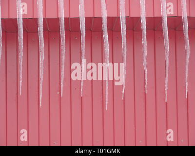 Long icicles on the red wall Stock Photo