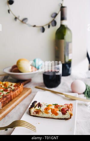 Homemade pie ( quiche) , with ricotta, and fresh colored tomatoes ,cut in slice in a dish with golden fork, glass of wine,rectangular shapes, frontal  Stock Photo