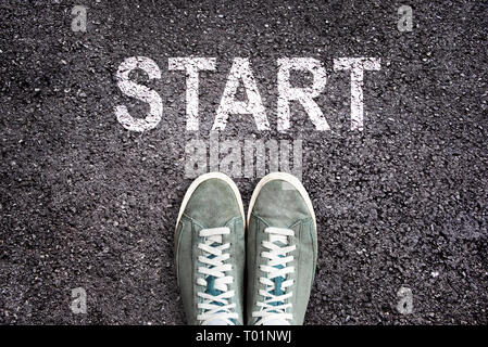 Sneaker shoes and the word START written  on asphalt ground, new life concept Stock Photo
