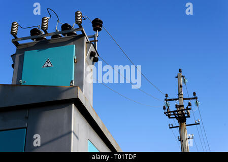 Image of an electrical substation and power lines set against a blue sky outdoors during the day Stock Photo