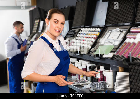 Positive glad female car painter preparing paints for paintwork in modern auto repair shop Stock Photo