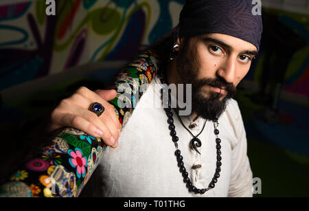 Dark close up portrait of a man with piercings and bandana. Stock Photo
