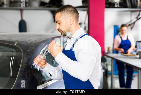 Professional mechanic performing dent repair on car body before painting in auto workshop Stock Photo