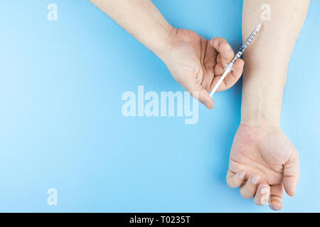 The addict colitizes herself with a syringe in her hand Stock Photo