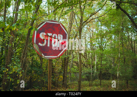Stop sign - old rusty, frayed, scratched red road sign in radioactive zone in Pripyat city. Chornobyl exclusion zone Stock Photo
