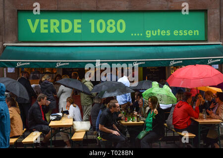Vienna, Austria, September , 14, 2019 -  Even under rain Viennans enjoy happy hour holding a umbrella at Verde 1080 after a day at work  Stock Photo
