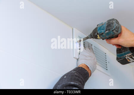 Close up man hand installing vent cover from ceiling Mounted Air Conditioner. Stock Photo