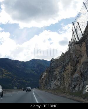 COLORADO, USA—OCTOBER 2017:  Winding roads with wire netting placed on the cliff wall to stop rocks from falling into the highway  along Interstate 70 Stock Photo
