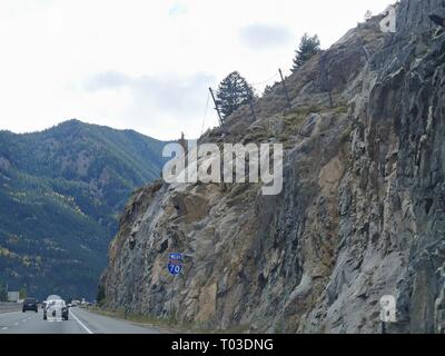 COLORADO, USA—OCTOBER 2017:  Wide shot of winding roads with wire netting placed on the cliff wall to stop rocks from falling into the highway  along Stock Photo